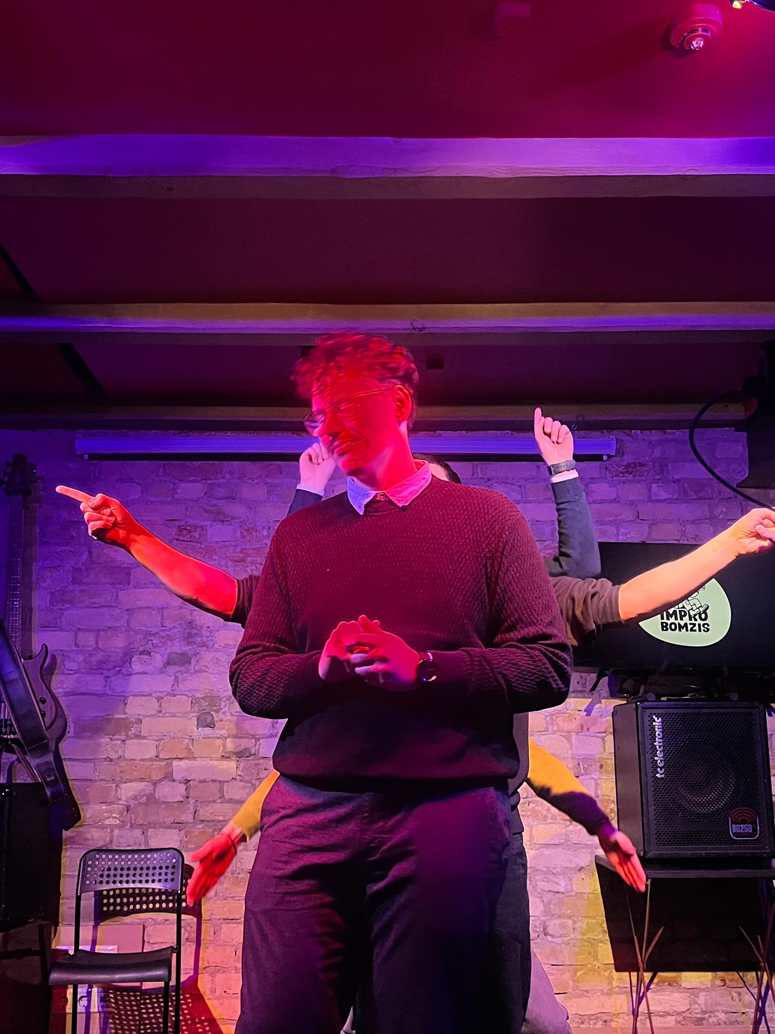 A performer mid-scene under red and purple stage lights