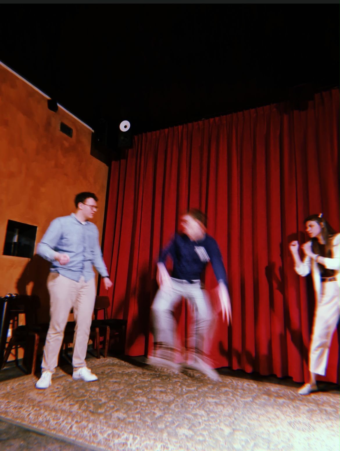 A blurred, fast-moving moment on stage in front of a red curtain